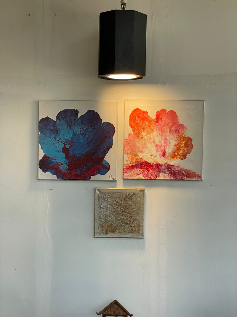 Three abstract paintings on a wall with a black pendant light.