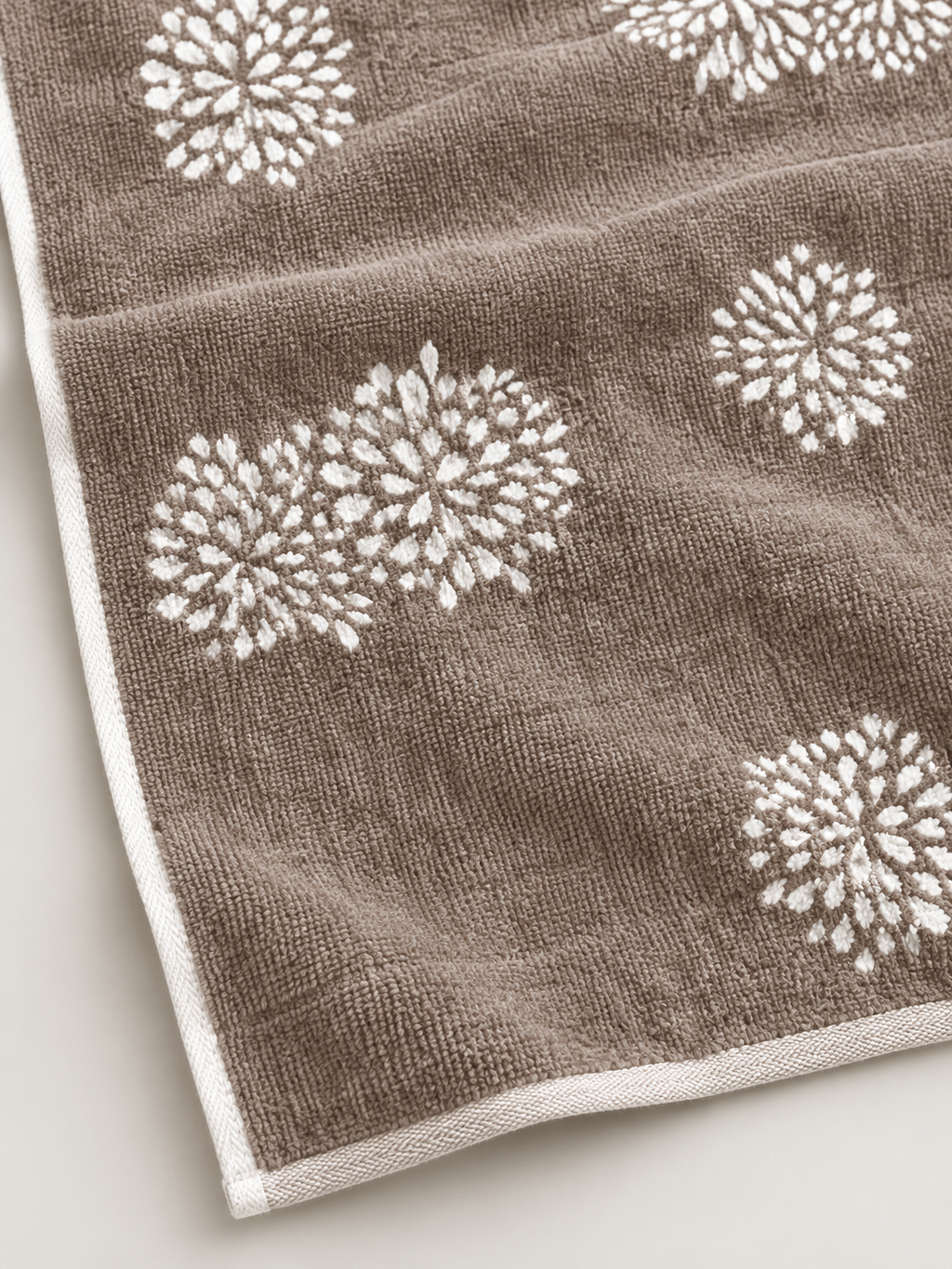 Close-up of the woven texture and white floral motif on a brown bath towel
