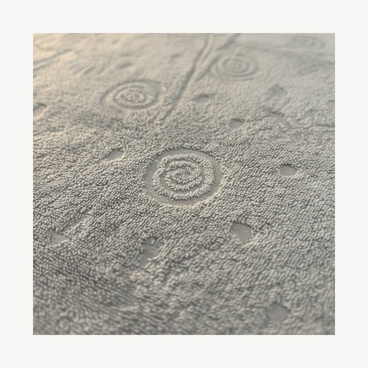 Close-up of raised shell jacquard pattern on grey cotton terry cloth fabric
