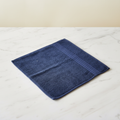 Navy blue face towel folded flat on marble surface