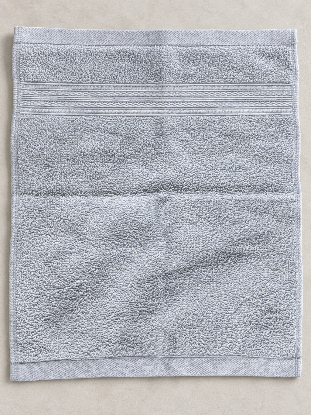 Close-up of the subtle woven bands and soft texture on a light gray face towel