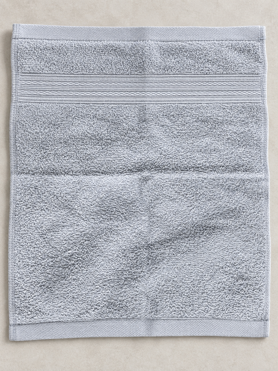 Close-up of the subtle woven bands and soft texture on a light gray face towel
