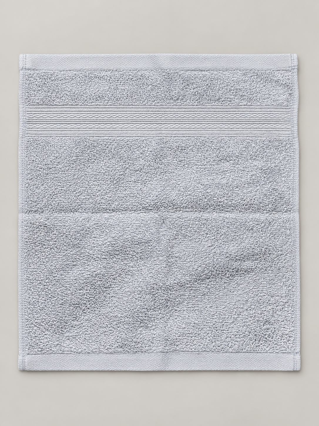 Light gray face towel with subtle woven bands and finished border measuring 28 x 30 cm