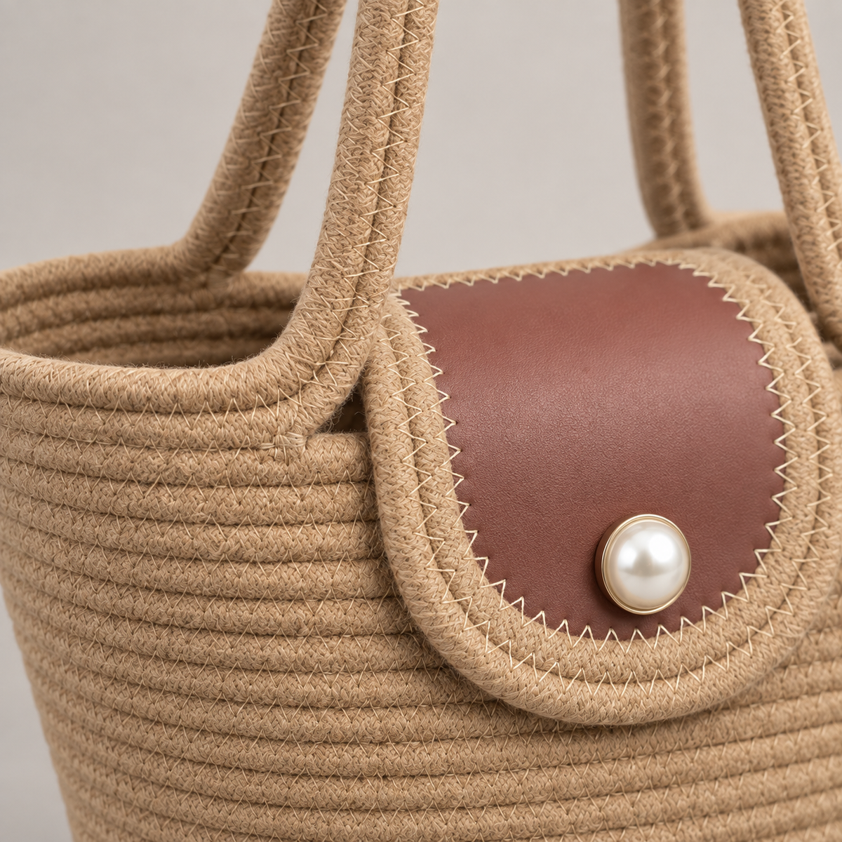 Close-up of tan rope stitching, dusty rose flap and pearl-style snap