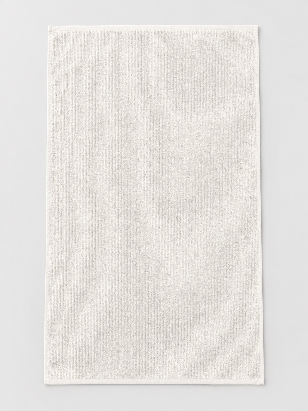 White ribbed bath towel measuring 76 x 130 cm on a light grey studio background