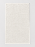 White ribbed bath towel measuring 76 x 130 cm on a light grey studio background