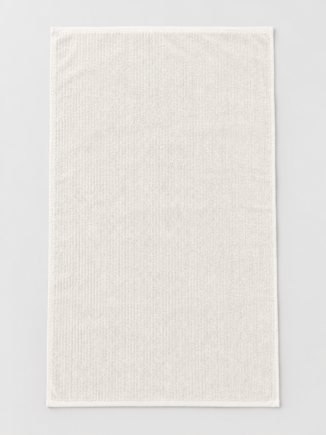 White ribbed bath towel measuring 76 x 130 cm on a light grey studio background
